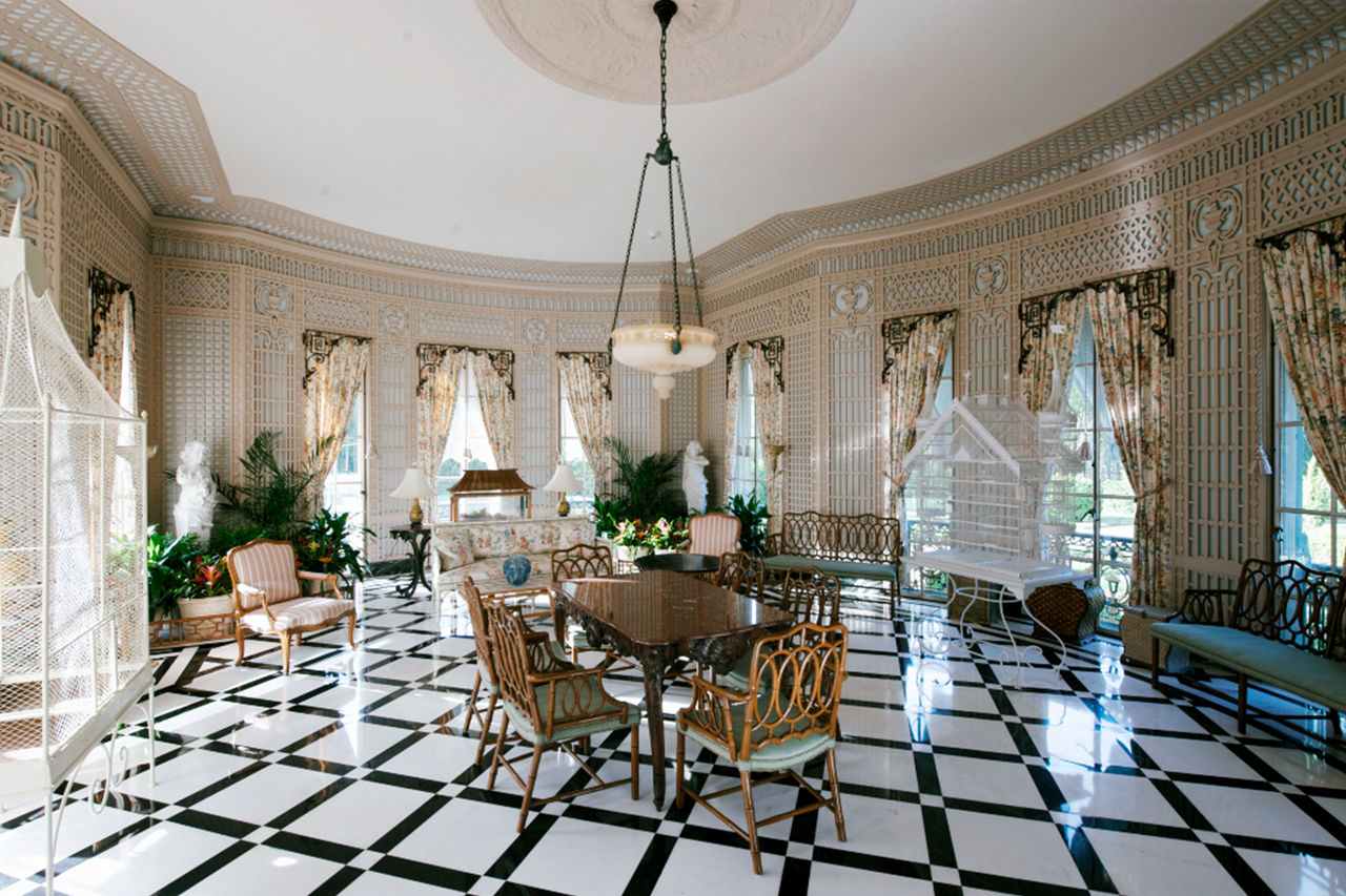 The Conservatory has a black-and-white checkered floor and a table and chairs in the middle with lots of windows and sunlight. 